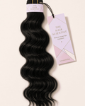 Natural color body wave human hair bundle with The Hair Scientist wrap and hang tag on a pale background