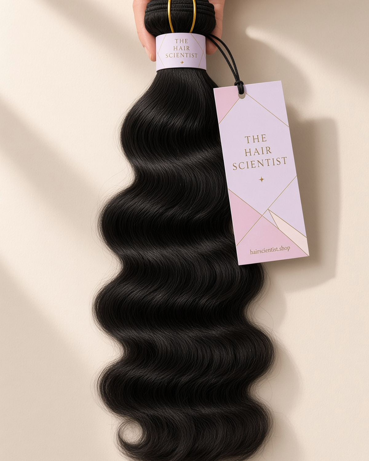 Natural color body wave bundle held in hand, with The Hair Scientist wrap and hang tag